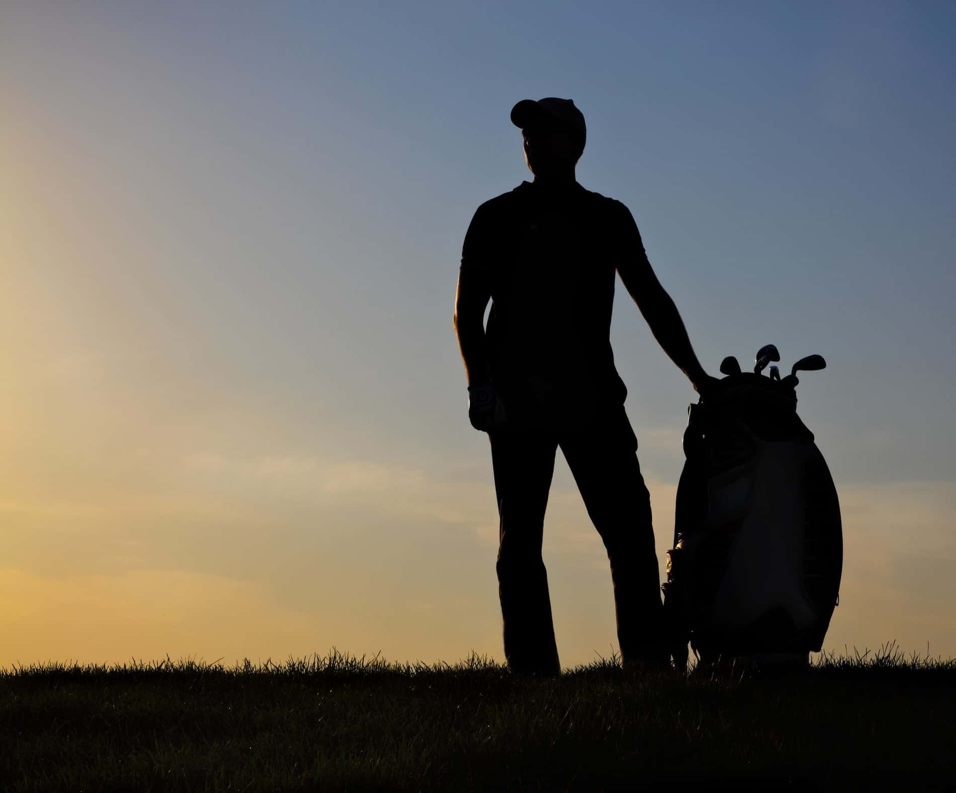 Male golfer playing golf at sunset