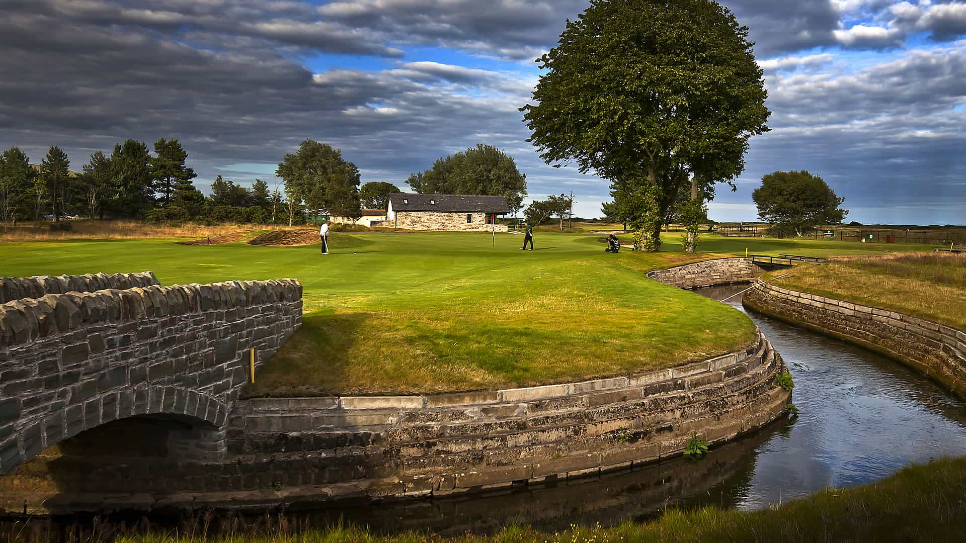 A Golf Course With A Bridge Over A Stream.